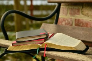 A picture of a Bible and a couple of other books on a park bench